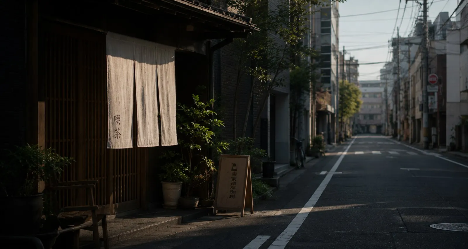 Rue calme de Tokyo au petit matin, noren devant une façade en bois.